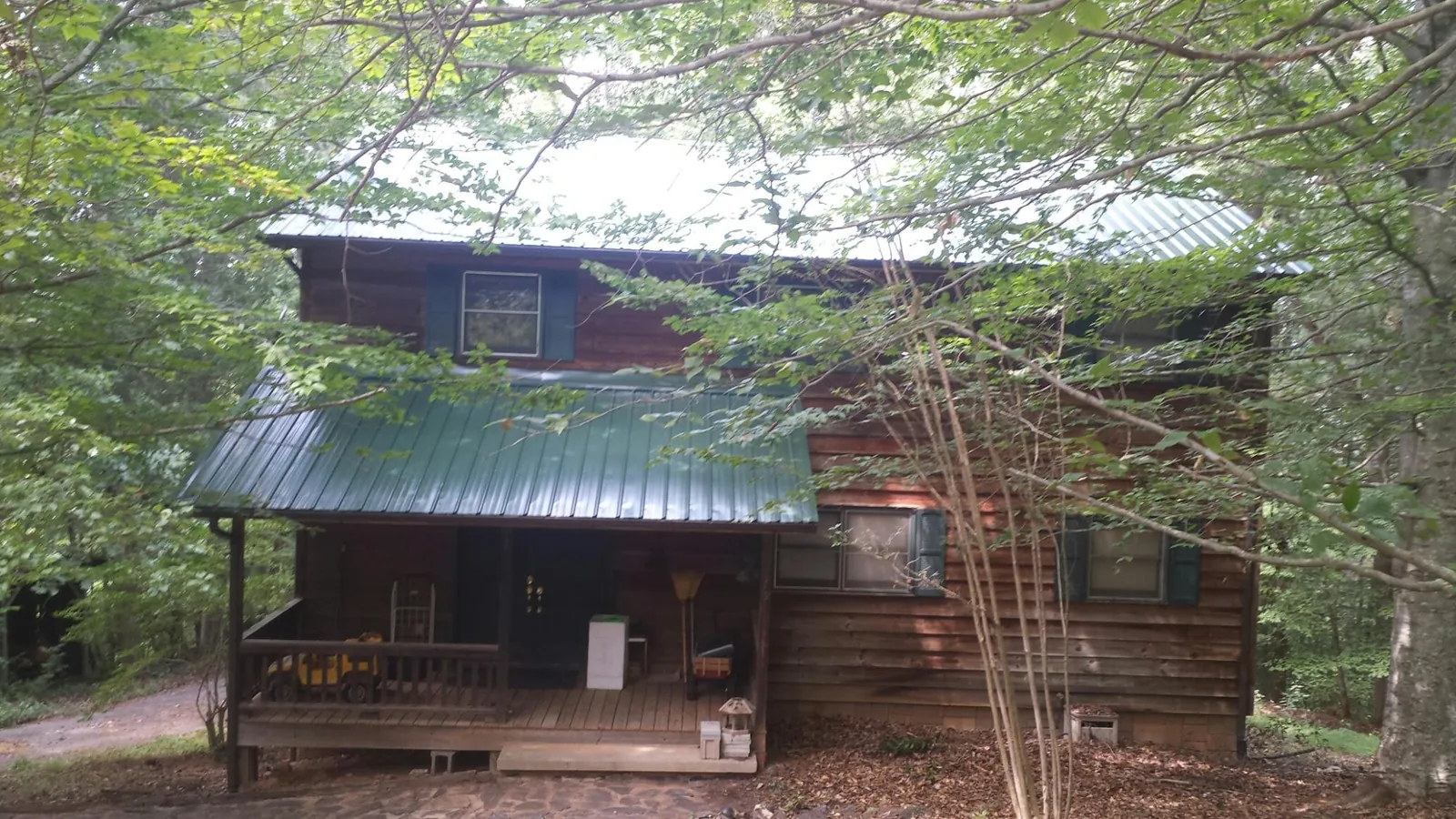 Green metal roof and covered porch on a log cabin in Glenwood