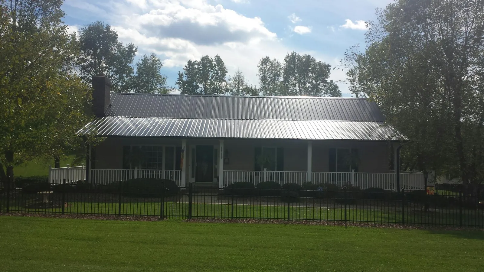 Gray metal roof on a brick ranch with a full width front porch — Gutter Guard Installation work by our crew in Glenwood